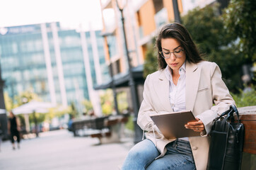 Portrait of a business woman using digital tablet during quick break in front a corporate building.