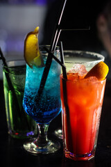 delicious creative bright cocktails booze alcohol with a straw are on the table in a club or a lighted bar