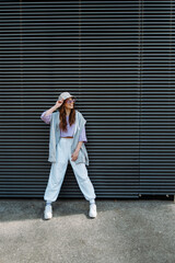 Fashionable funky caucasian girl dancer in sportswear is performing outdoor street dancing motion . 