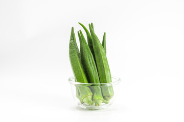 fresh green okra isolated on white background. okra in glass bowl. healthy vegetables.