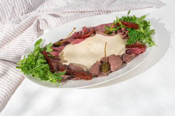 Vitello tonnato italian dish. Thin sliced veal with tuna sauce, capers and coriander