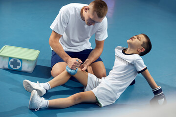 Personal coach, team trainer provides first aid to an athlete with a leg injury. Boxing training in...