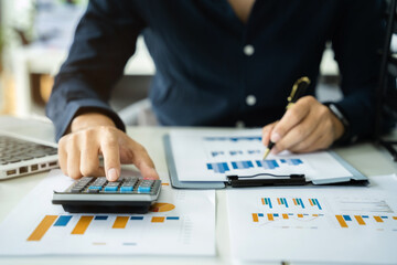 Businessman calculate and analyzing graph document financial with laptop in office.