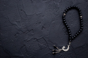 Black Muslim rosary with silver crescent moon. Islamic background