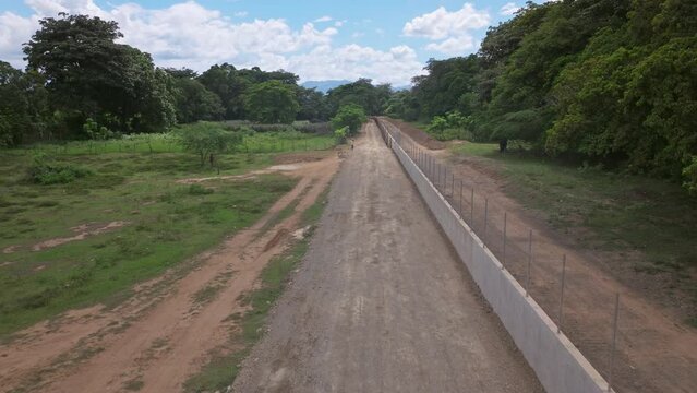 People divided by new concrete border wall between Haiti and Dominican Republic. Aerial forward low altitude