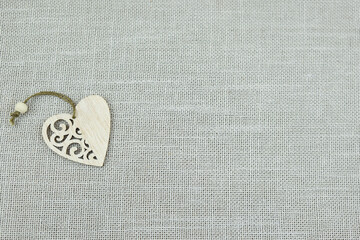 Heart made of wood on a gray background. Beige texture background. Natural cotton burlap.