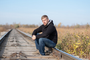 Fototapeta premium a man sits on the railroad tracks. man on the railroad tracks