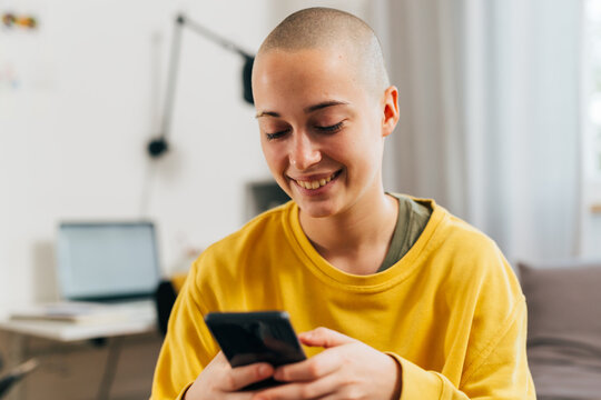 gen z bald female using mobile phone in her room