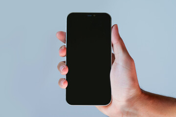 empty screen mobile phone. Close-up hand holding cell phone isolated on blue background. hand holding a blank-screen smartphone.