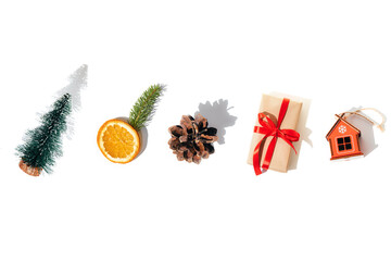 Background with isolated gift, toy house, dry orange, fir, pine cone with shadows on a white background. Flat lay Christmas pattern