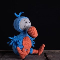 Dodo bird in blue and orange on black background, fun colors, amigurumi toys, handmade, crochet, hobby, copy space © Katrien