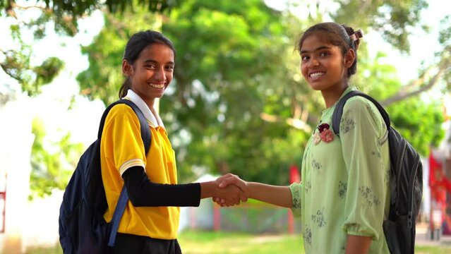 Shaking hands of two student girl outdoor. Happy positive studen, two university students shaking hands, standing with backpacks, smiling. Beautiful friendly girl and young handsome guy greeting.