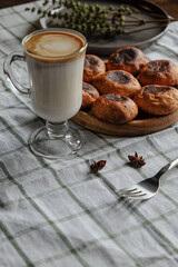 Pastries with coffee and milk in a glass on a white checkered towel