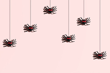 Spiders with cute red hair bows, creative pattern on a pastel pink background. Halloween party inspired minimalistic layout. 