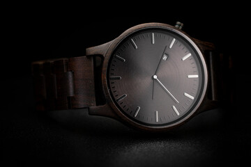 Dark brown wooden watch on a clean black background