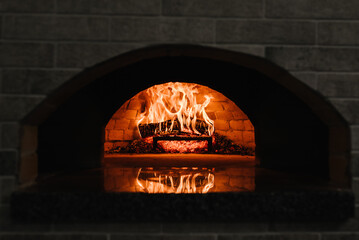Firewood burning in the oven. Wood-fired oven. Image of a brick pizza oven with fire. A traditional...