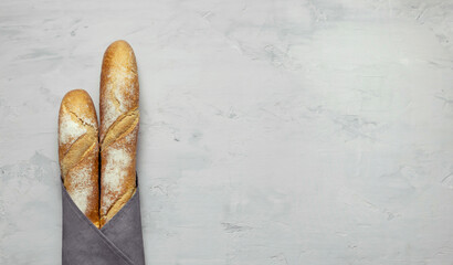 wheat baguette in a gray napkin on a gray background with a copy space