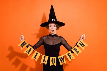 Photo of astonished pretty lady hands hold halloween flags isolated on orange color background