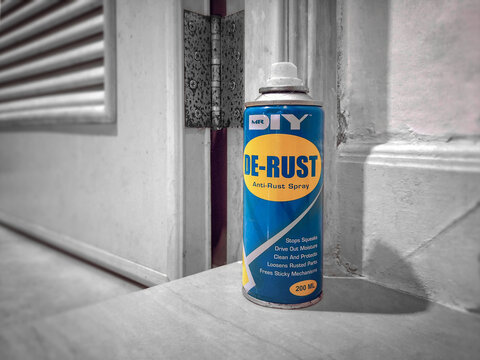 BANGKOK, THAILAND - OCTOBER 13, 2020: Can of Mr. DIY De-Rust Lubricant Spray next to a Rusty Door Hinge.