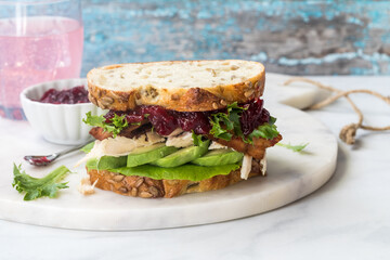 A delicious turkey and bacon club sandwich with avocado and cranberry sauce.