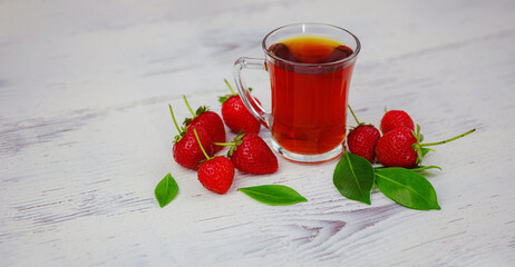 Fresh organic strawberries and black tea in glass cup , over white background. Vegetarian healthy food concept.