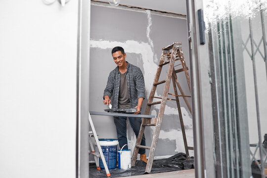 Ultra wide shot of Asian man painting a wall doing home renovation