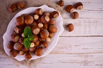 Hazelnut nuts in a plate on a white wooden background.Flet ley.  © Olivka888