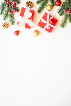 Christmas holiday decorations at white background with copy space. Gift boxes, fir tree, baubles and others. Flat lay composition.