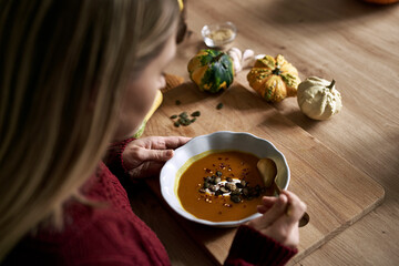 Close up of caucasian woman start eating warming pumpkin soup