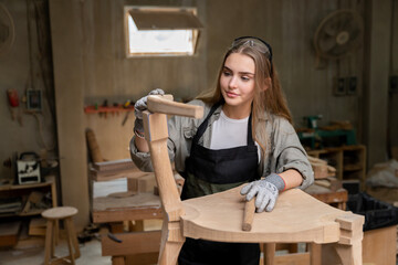 A female carpenter assembling a chair she had designed and built. At the furniture factory found inside her house