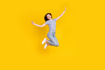 Fototapeta na wymiar Full length photo of nice young girl spread hands plane jumping ad poster wear stylish striped garment isolated on yellow color background