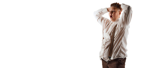 Shocked teen boy, overweight model in white shirt and suspenders isolated over white studio...