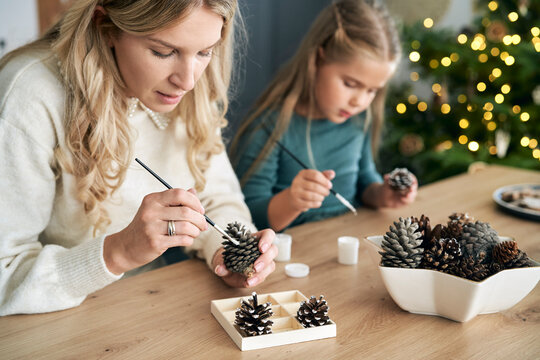 Caucasian woman and daughter decorating cone with white paint