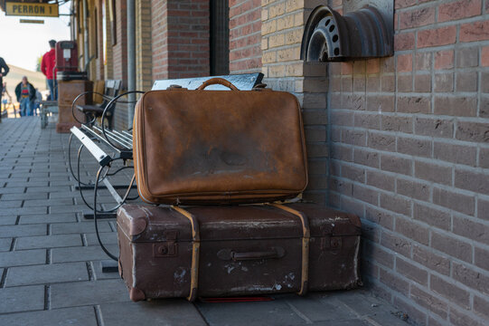 Old suitcases piled up on a station platform.