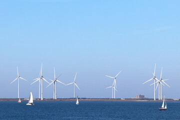 Wind power: sailing ships on the Eastern Scheldt estuary and wind turbines on the storm surge barrier, Netherlands