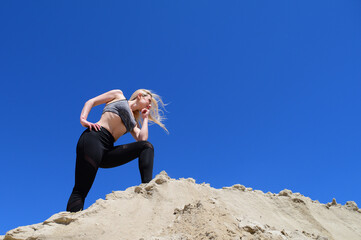 Bottom view of an athletic blonde woman on the sand in the desert. Thoughtful woman. woman workout. Workout nature