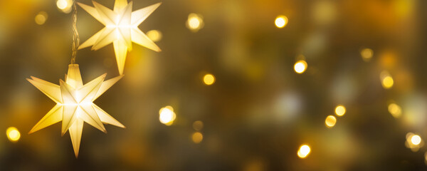 hanging shiny christmas stars on bright golden background, festive decoration for christmas eve,...