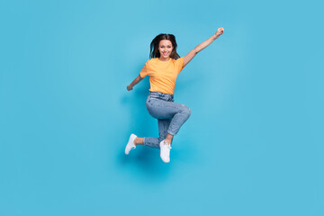 Fototapeta na wymiar Full length photo of sweet adorable girl dressed yellow t-shirt jumping high rising fist isolated blue color background