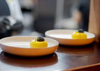 Yellow cheesecake dessert in white plate with black chocolate. 