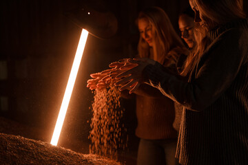 Shot of farmers women scattering grains near led lamp and wheat grain mountain.
