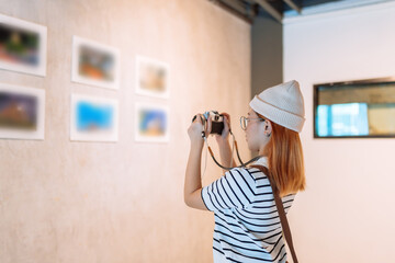 Woman visiting art gallery her looking pictures on wall watching photo frame painting at artwork...