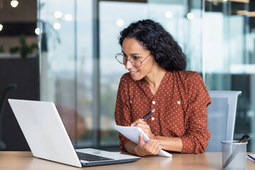 Young beautiful and successful business woman studying remotely sitting in the office, Hispanic...