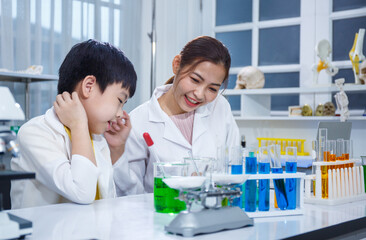 Asian boy and female teacher learn to experiment with mixing liquids in tubes. Science