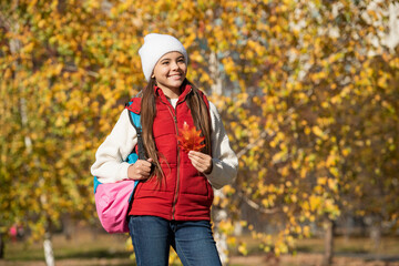 smiling teen girl at school time outdoor in autumn season with backpack