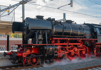 Fototapeta na wymiar Antique steam locomotive, driving through a station.