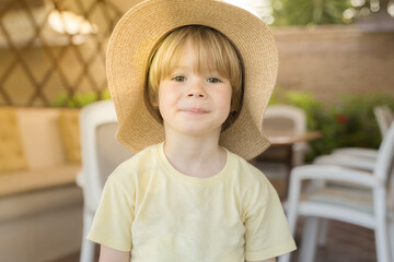 The little boy in a straw hat in a sunny day outdoors