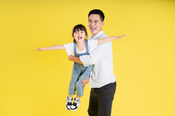 image of two happy father and daughter playing, isolated on yellow background