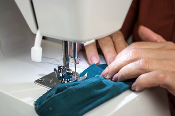Close up woman sewing clothes with sewing machine indoor