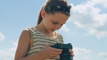 Young photographer shooting landscape. Girl taking pictures of nature, watching result, upgrading...