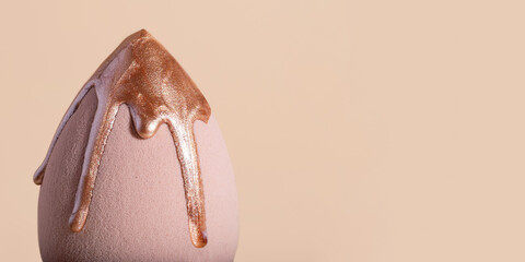 Closeup photography of beauty blender with dripping bronzer on it.Neutral beige background,large...